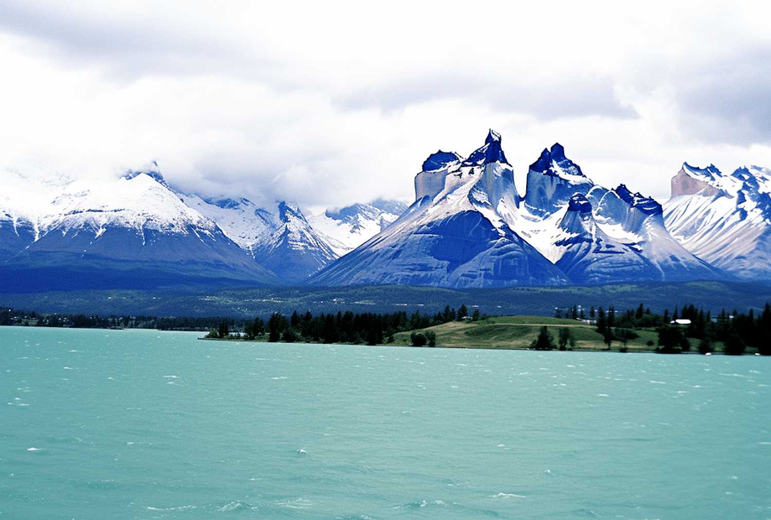 Jagged snow-capped peaks rising above a turquoise lake