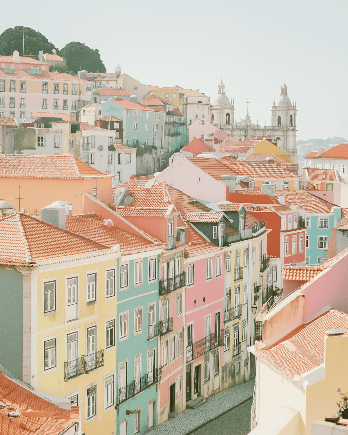 Pastel townhouses with terracotta roofs climbing towards a domed church