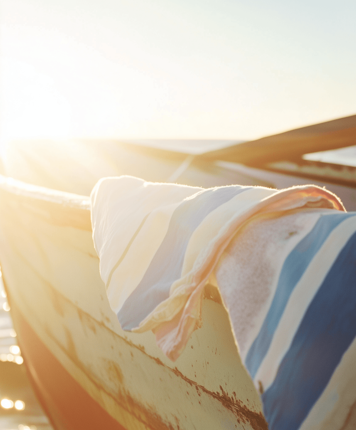 A pastel wooden boat with a striped towel in warm sunlight